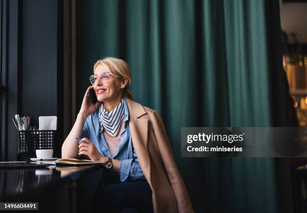 happy business woman talking on a mobile phone in the cafe - mobile device on table stockfoto's en -beelden