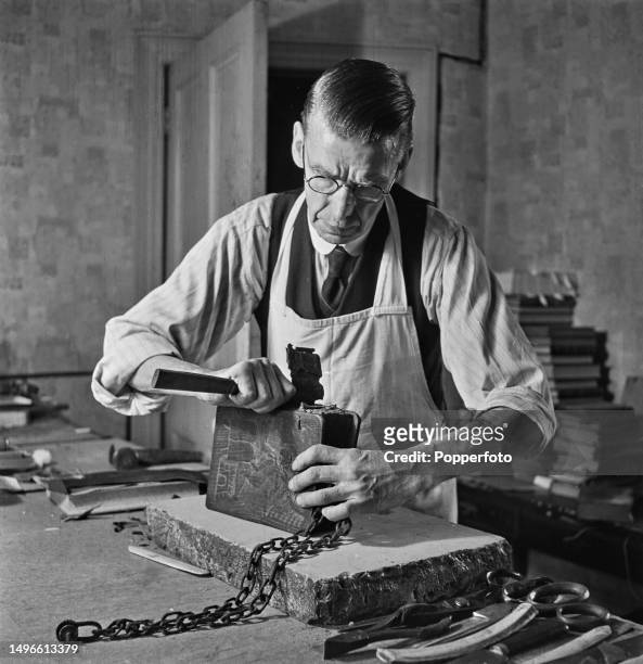 English bookbinder Walter Forbes carefully strips back the torn back from a valuable and rare chain bible at his home workshop, 95 Earlsfield Road in...