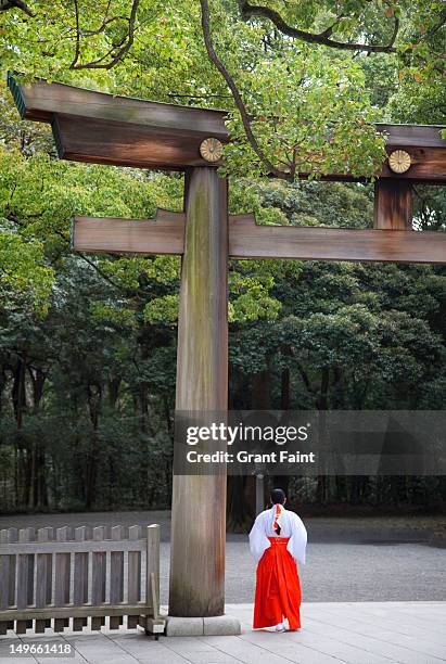 a shinto priestess and a torii gate at meji shrine - meji shrine stock pictures, royalty-free photos & images