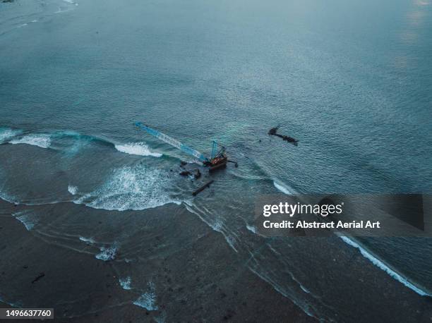 aerial shot showing a crane working on the edge of the ocean, bali, indonesia - dredger stock pictures, royalty-free photos & images