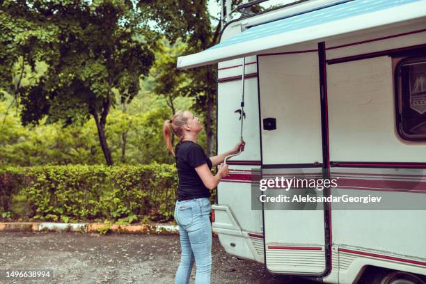 side view of beautiful blond female pulling up awning of rv motorhome - awning stock pictures, royalty-free photos & images