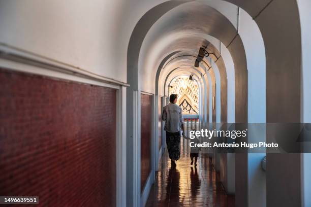 woman and child walking down a hallway inside a buddhist temple in bangkok - cult stock pictures, royalty-free photos & images