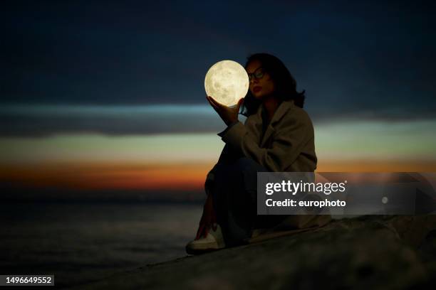 young lady playing with a moon shaped artificial lamp outdoors - full moon stock pictures, royalty-free photos & images