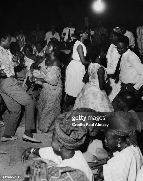 Young Nigerians, dressed in both traditional clothing, shirts and ties as well as more casual clothing, dancing at a social club in Nigeria, circa...