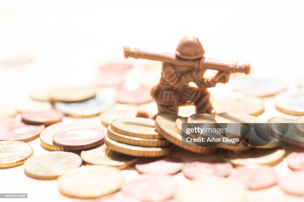 Soldier with a bazooka figurine on many coins. Concept of investment in defence equipment and army.