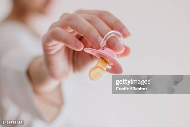 midsection of pregnant woman holding pacifier - pacifier stock pictures, royalty-free photos & images