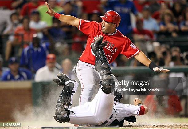 Kendrys Morales of the Los Angeles Angels of Anaheim is tagged out at the plate by Mike Napoli of the Texas Rangers on a throw by Nelson Cruz on...