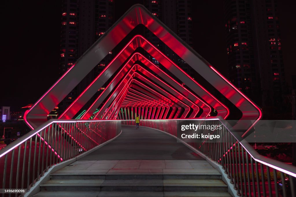Pedestrians crossing a pedestrian bridge with light effects