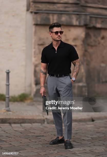 Andre Hellmundt wearing Saint Laurent black leather business clutch, Gant black leather loafer, Hechter Paris grey suit pants, Massimo Dutti black...