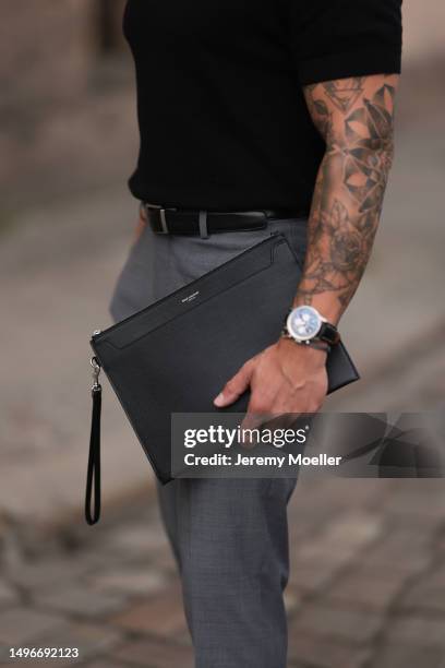 Andre Hellmundt wearing Saint Laurent black leather business clutch, Gant black leather loafer, Hechter Paris grey suit pants, Massimo Dutti black...