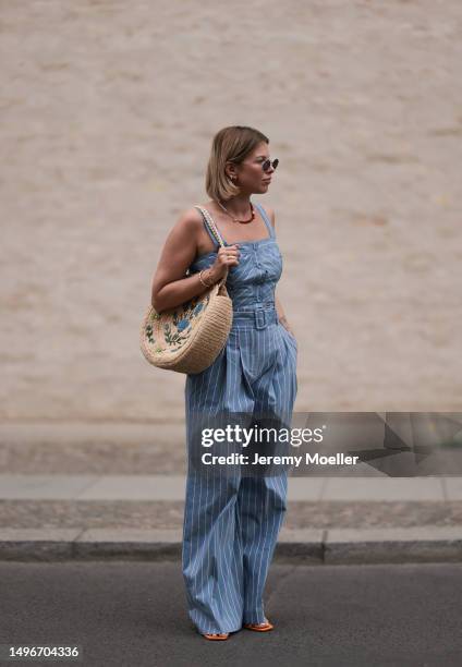 Aline Kaplan wearing Veronica Beard striped blue, green, white cropped top and Veronica Beard matching wide leg pants, Sezane raffia round bag, &...