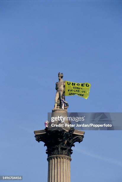 Protesters from the environmental group Greenpeace unfurl a banner after climbing to the top of Nelson's Column during a protest against the upcoming...