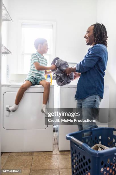 father and son doing laundry in laundry room - man washing basket child stock pictures, royalty-free photos & images