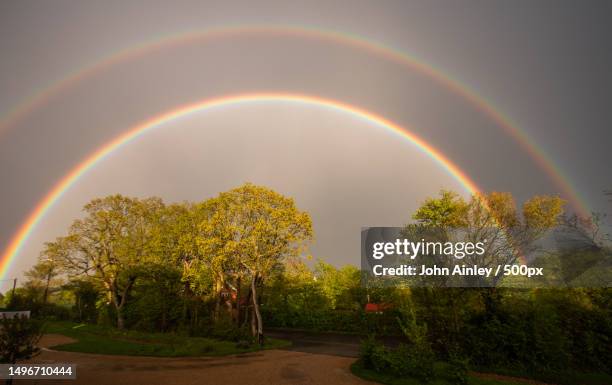 scenic view of rainbow over trees against sky,badingham,united kingdom,uk - arco iris doble fotografías e imágenes de stock