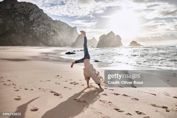 girl doing a cartwheel in sand at the beach - cartwheel stock pictures, royalty-free photos & images