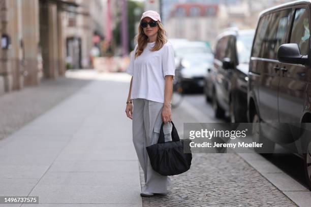 Sonia Lyson wearing The Frankie shop grey wide leg cargo pants, Weekday white cropped oversized shirt, Vee Collective Carba small black puffer bag,...