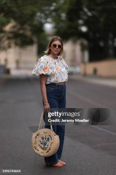 Aline Kaplan wearing Baum & Pferdgarten wide leg blue denim pants, & other stories white flower pattern cropped blouse and orange summer heels and...