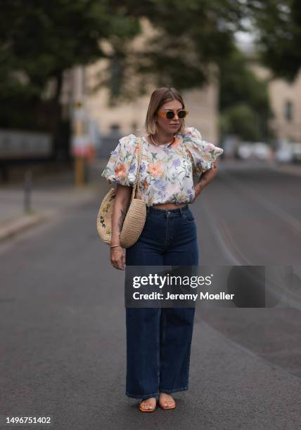 Aline Kaplan wearing Baum & Pferdgarten wide leg blue denim pants, & other stories white flower pattern cropped blouse and orange summer heels and...