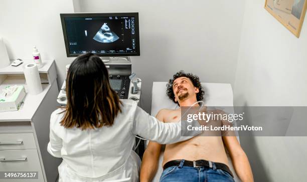 mann mit einer ultraschalluntersuchung des herzens - echokardiogramm stock-fotos und bilder