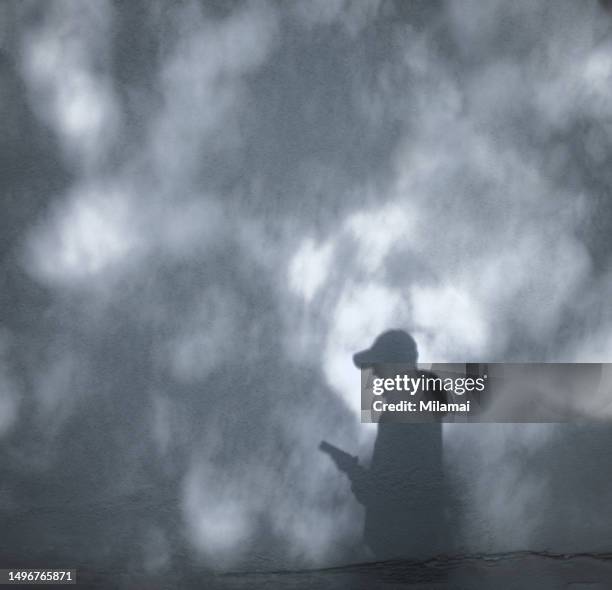 shadow of person with smart phone and cap - turku finland stock pictures, royalty-free photos & images