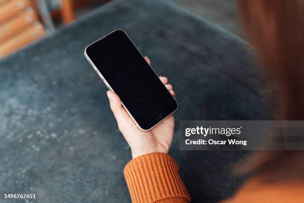 over the shoulder view of young woman using smartphone - teléfono inteligente fotografías e imágenes de stock