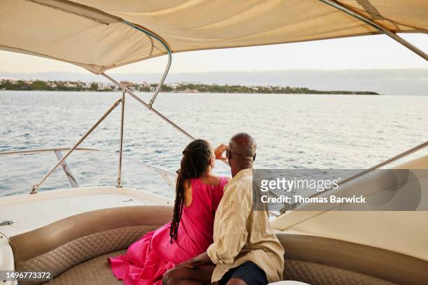 medium shot couple taking photo of sunrise from flybridge of yacht - luxury cruise relaxing stock pictures, royalty-free photos & images