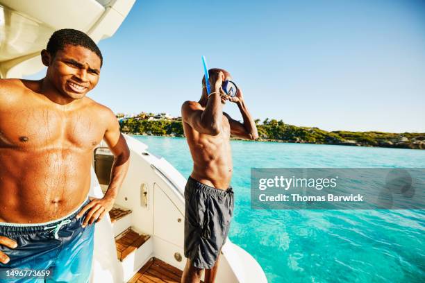 medium wide shot father putting on dive mask on swim step of yacht - family summer holiday stock pictures, royalty-free photos & images