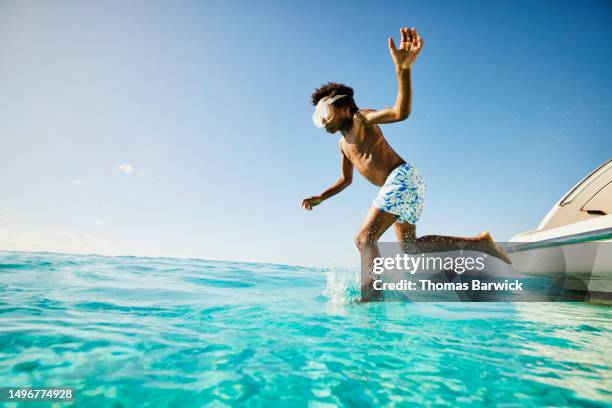 wide shot young boy jumping into ocean from swim step of yacht - quintana roo stock-fotos und bilder