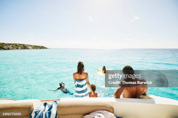 wide shot rear view family playing in ocean and on swim step of yacht - quintana roo stock-fotos und bilder