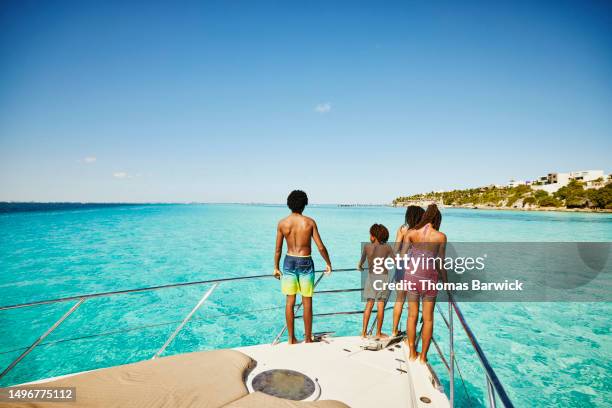 wide shot siblings standing at bow of yacht during family vacation - quintana roo stock-fotos und bilder