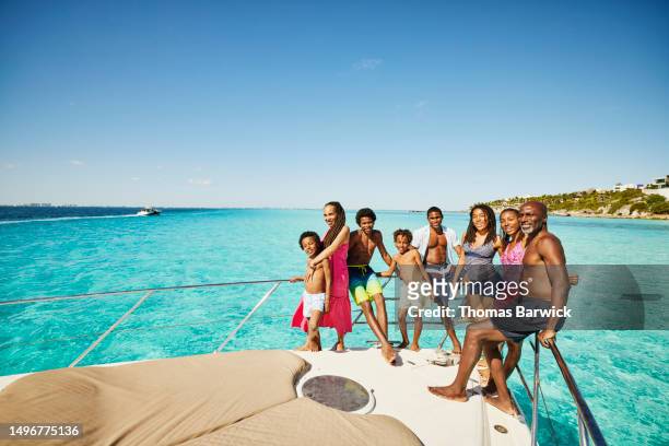Wide shot of smiling family standing at bow of yacht during vacation
