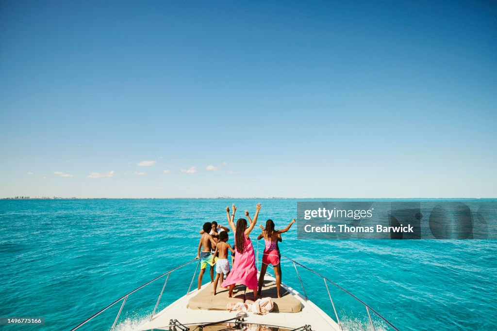Wide shot of smiling family dancing on bow of yacht during vacation