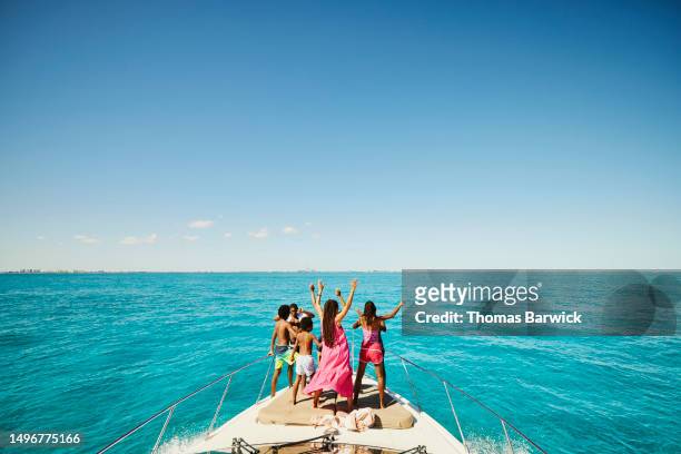 Wide shot of smiling family dancing on bow of yacht during vacation