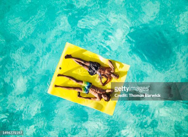 Wide shot of father and son relaxing on swim float in ocean