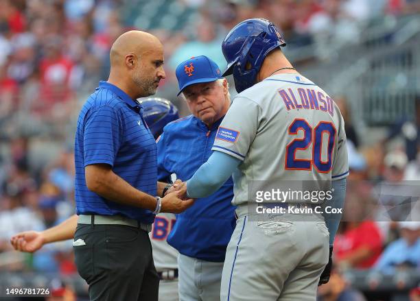 Pete Alonso of the New York Mets converses with manager Buck Showalter and the trainer after he is hit by pitch in the first inning against Charlie...