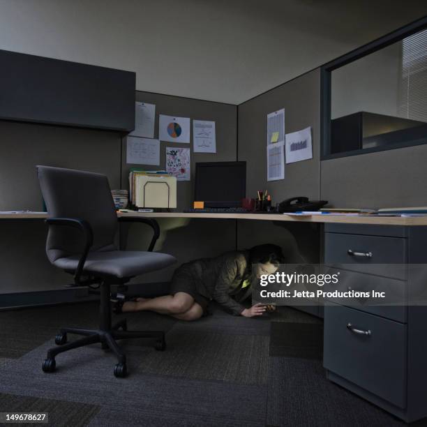 mixed race businesswoman using, cell phone underneath desk - hiding stock pictures, royalty-free photos & images