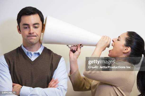 businesswoman shouting with megaphone into co-worker's ear - ignoring stock-fotos und bilder