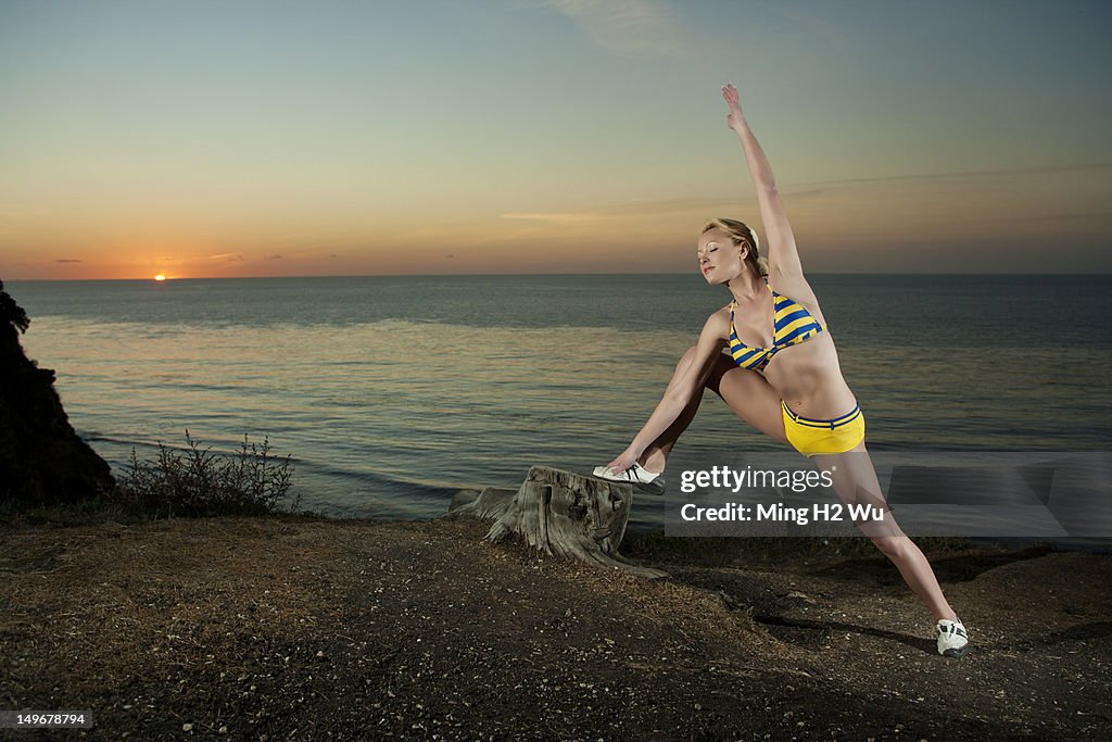 Caucasian woman stretching near ocean