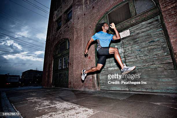 male athlete running on sidewalk - running man profile stock pictures, royalty-free photos & images