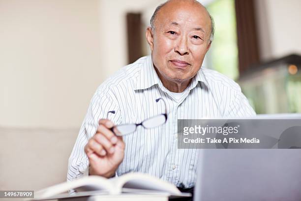 chinese man with book and laptop - só um homem idoso - fotografias e filmes do acervo