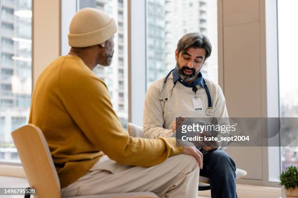 aufnahme eines arztes, der eine konsultation mit einem patienten in seinem büro hat - clinic canada diversity stock-fotos und bilder