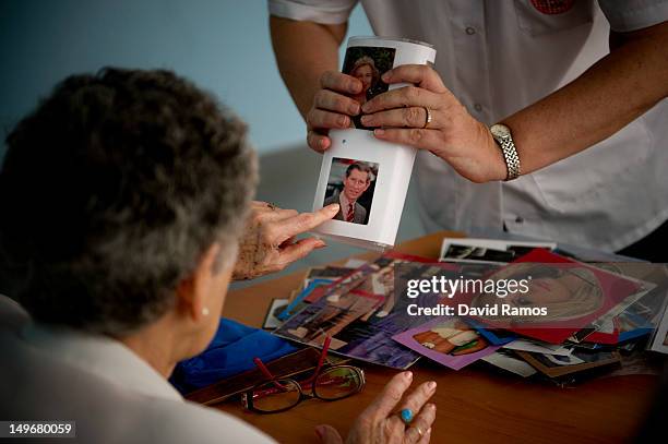 Social worker Nuria Casulleres shows a portrait of Prince Charles, Prince of Wales to an elderly woman during a memory activity at the Cuidem La...