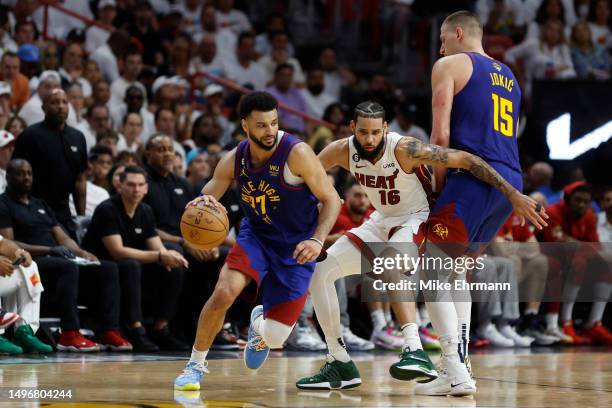 Jamal Murray of the Denver Nuggets dribbles past a screen set by Nikola Jokic against Caleb Martin of the Miami Heat during the fourth quarter in...