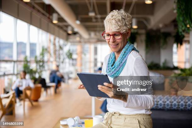 happy businesswoman smiling at a coworking while using a tablet - cool stock pictures, royalty-free photos & images