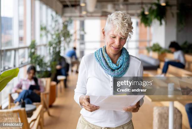 casual businesswoman working at the office and reading documents - business people and paper imagens e fotografias de stock