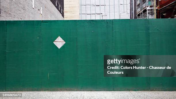palisade in patinated green wood panels in front of a construction site and cement sidewalk in manhattan, new york state, united states - palissades stockfoto's en -beelden