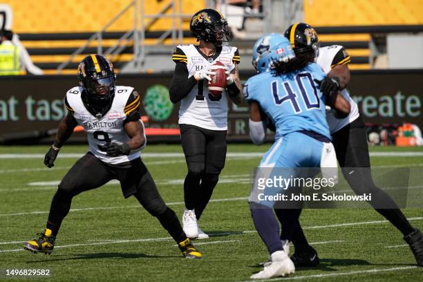 Bo Levi Mitchell sets up pass as James Butler of the Hamilton Tiger-Cats looks to help block Robbie Smith of the Toronto Argonauts at Tim Hortons...