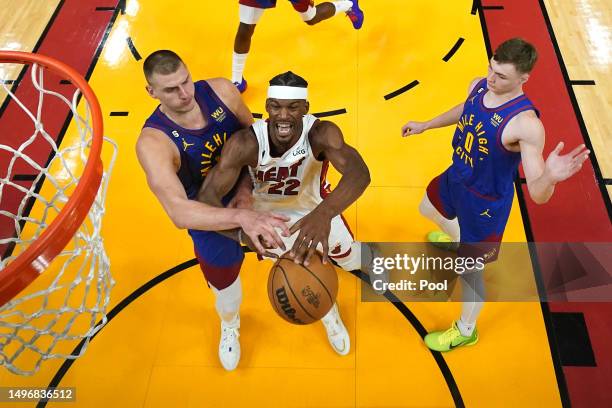 Nikola Jokic of the Denver Nuggets and Jimmy Butler of the Miami Heat compete for a rebound in the second half during Game Three of the 2023 NBA...