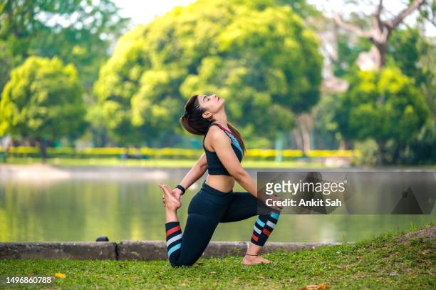 woman doing yoga and stretching exercise at park. - yoga day stock pictures, royalty-free photos & images