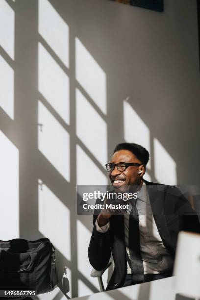 happy businessman sitting near wall at office - businesswear stock pictures, royalty-free photos & images